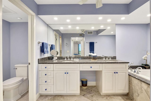 bathroom featuring tiled bath, vanity, and toilet