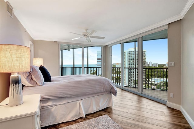 bedroom featuring access to exterior, ornamental molding, a water view, and expansive windows