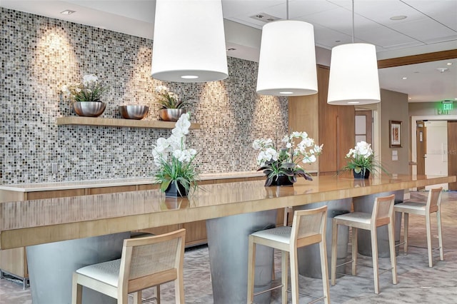 kitchen with a kitchen breakfast bar, kitchen peninsula, tasteful backsplash, and hanging light fixtures