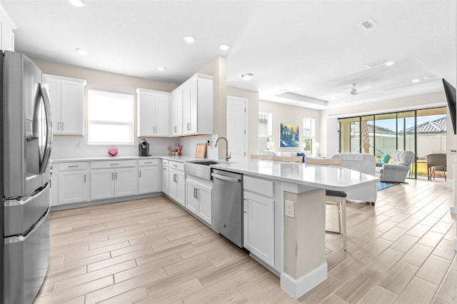 kitchen with sink, stainless steel appliances, white cabinets, and a breakfast bar area