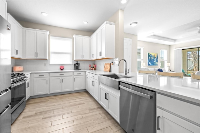 kitchen with stainless steel appliances, backsplash, white cabinets, ceiling fan, and sink