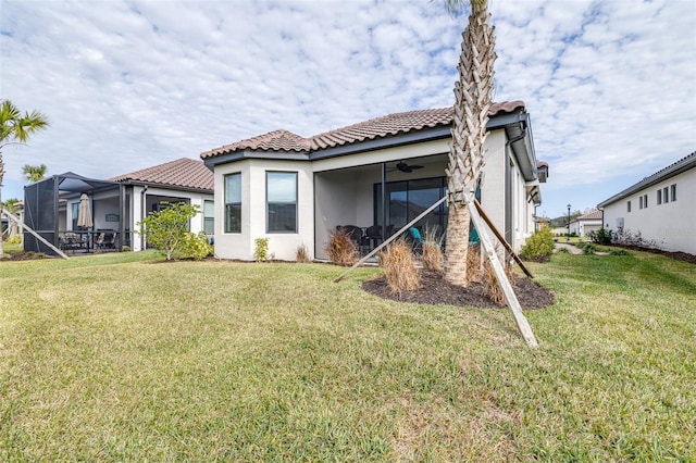 back of house with ceiling fan, a lanai, and a lawn