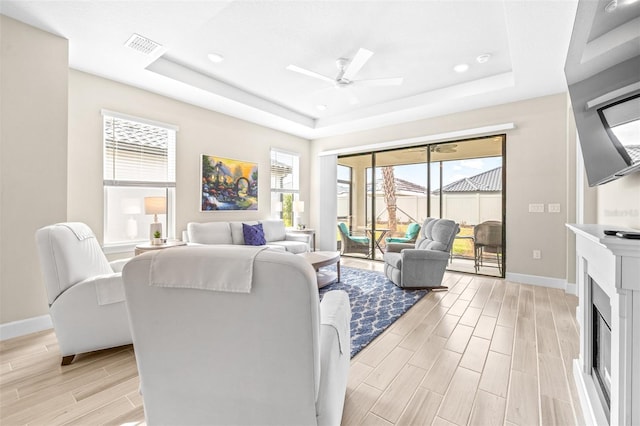 living room featuring ceiling fan and a tray ceiling