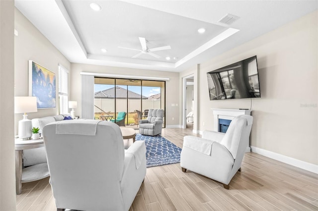 living room featuring a tray ceiling and ceiling fan