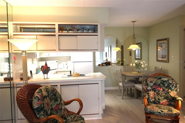 kitchen featuring decorative light fixtures, white fridge, light hardwood / wood-style floors, white cabinets, and black electric cooktop