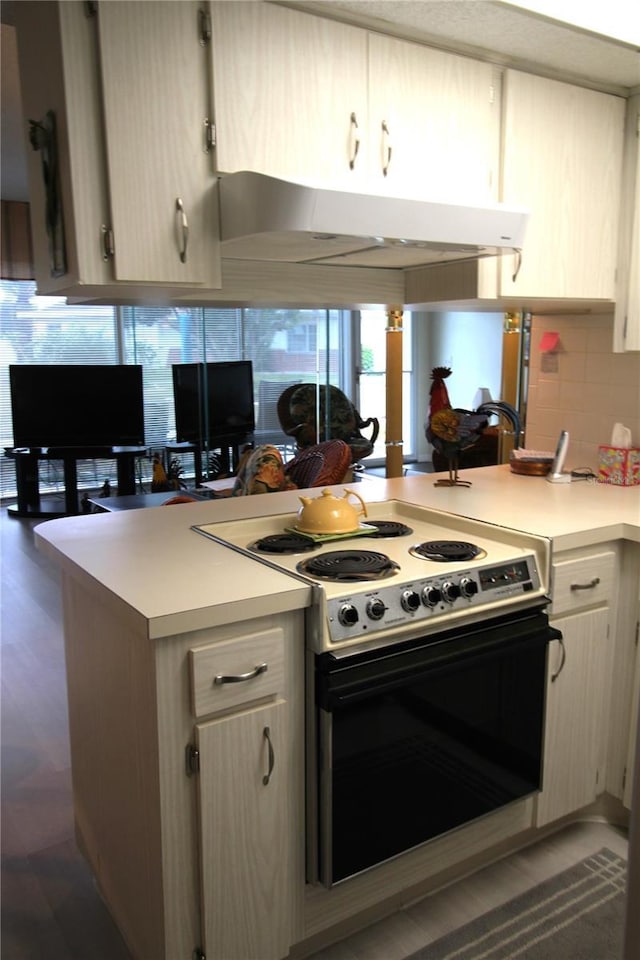 kitchen with decorative backsplash, light brown cabinets, kitchen peninsula, and range with electric cooktop