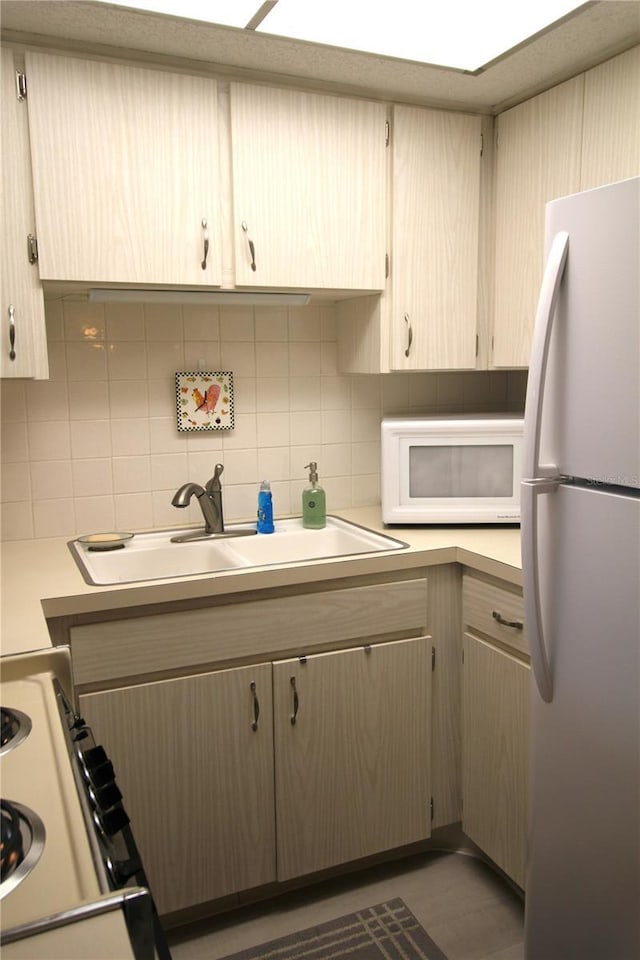 kitchen featuring tasteful backsplash, light brown cabinets, sink, and white appliances