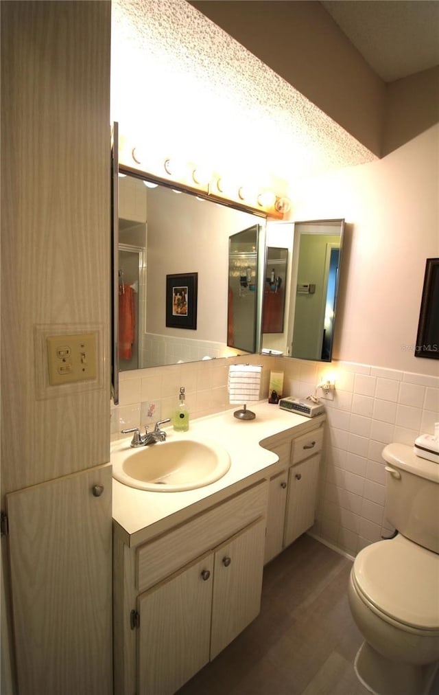 bathroom featuring toilet, tile walls, tile patterned floors, and vanity