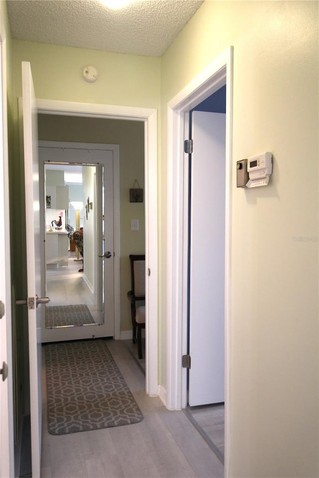 corridor with wood-type flooring and a textured ceiling