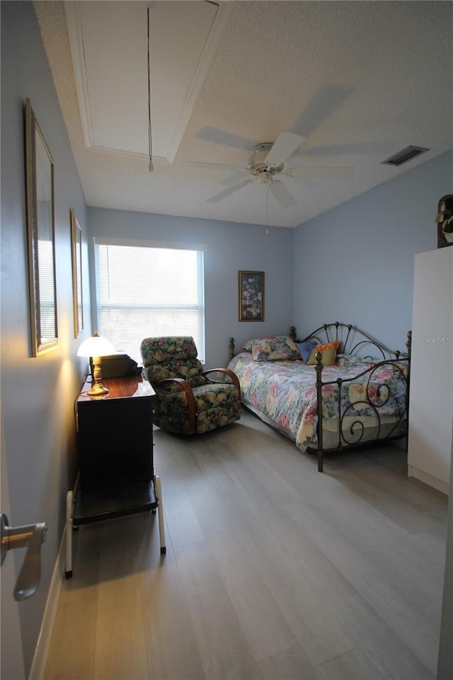 bedroom with a textured ceiling, ceiling fan, and wood-type flooring