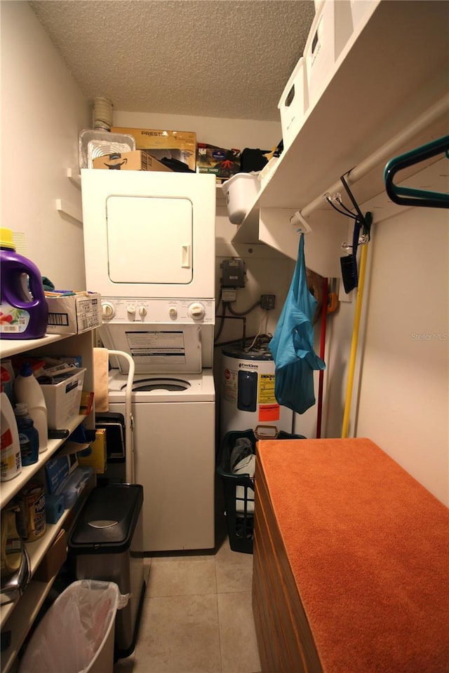 washroom with electric water heater, stacked washing maching and dryer, light tile patterned floors, and a textured ceiling