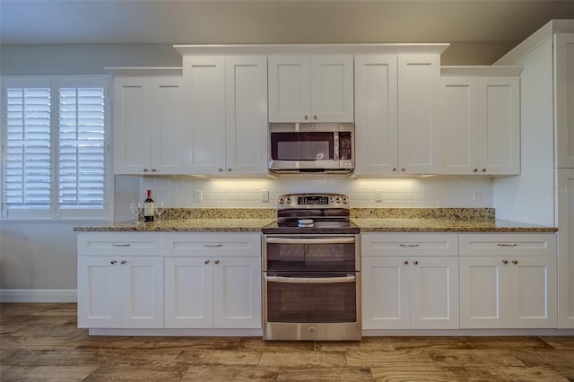 kitchen featuring stainless steel appliances, white cabinetry, backsplash, and light stone counters