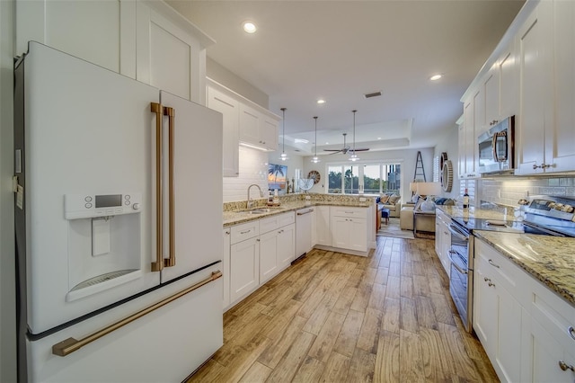 kitchen with tasteful backsplash, stainless steel appliances, white cabinets, and pendant lighting