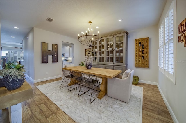 dining space featuring ceiling fan with notable chandelier and light hardwood / wood-style floors