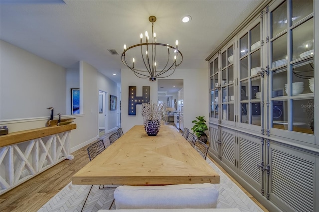 dining space featuring light hardwood / wood-style flooring and a chandelier