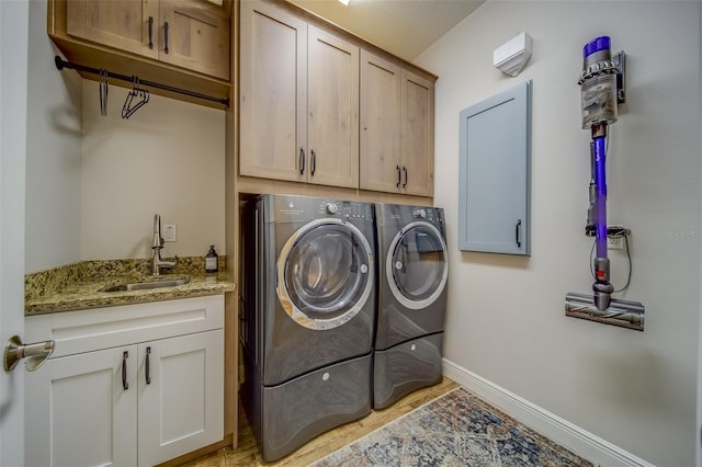 laundry room with washing machine and dryer, cabinets, light hardwood / wood-style floors, and sink