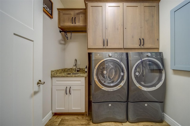 clothes washing area featuring cabinets, washing machine and clothes dryer, and sink