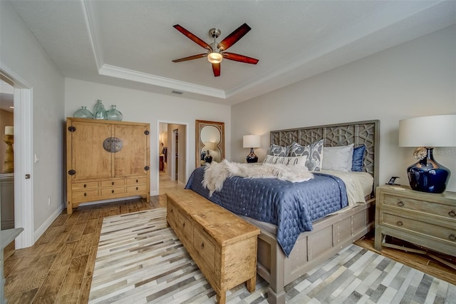 bedroom featuring ceiling fan, ornamental molding, and a tray ceiling