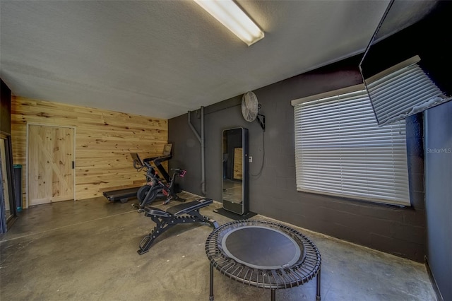 workout room featuring a textured ceiling and wooden walls