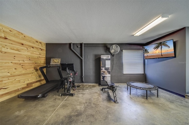 workout area with a textured ceiling and wooden walls