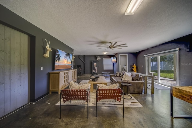 dining space featuring wooden walls, a textured ceiling, and ceiling fan