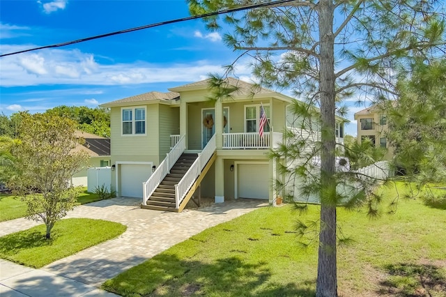 raised beach house featuring covered porch, a front lawn, and a garage