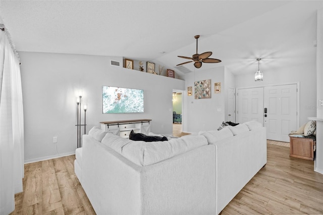 living room featuring ceiling fan, light hardwood / wood-style flooring, and vaulted ceiling