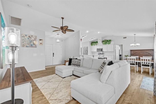 living room featuring ceiling fan with notable chandelier, lofted ceiling, and light hardwood / wood-style floors