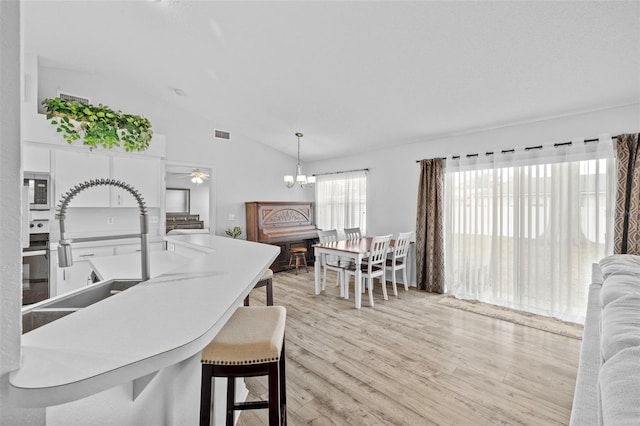 kitchen featuring vaulted ceiling, a chandelier, light hardwood / wood-style floors, hanging light fixtures, and sink