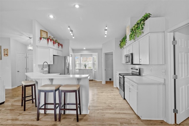 kitchen with stainless steel appliances, hanging light fixtures, white cabinets, light hardwood / wood-style flooring, and sink