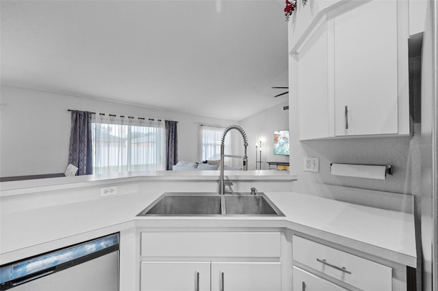 kitchen with sink, dishwasher, lofted ceiling, and white cabinetry