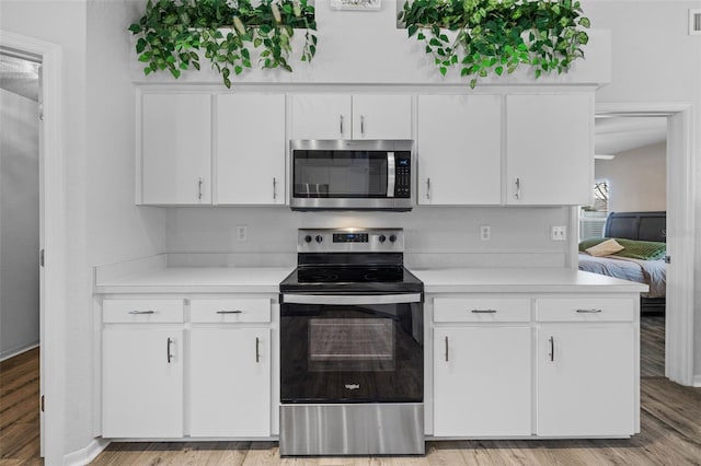 kitchen featuring light wood-type flooring, appliances with stainless steel finishes, and white cabinetry