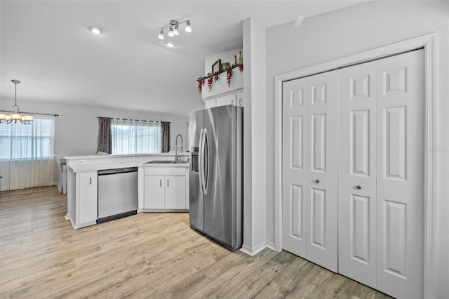 kitchen featuring sink, white cabinetry, kitchen peninsula, hanging light fixtures, and appliances with stainless steel finishes