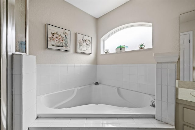 bathroom with tiled tub and vanity