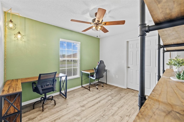 home office with a textured ceiling, ceiling fan, and light hardwood / wood-style floors