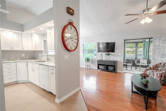 kitchen with sink, plenty of natural light, white dishwasher, white cabinets, and vaulted ceiling