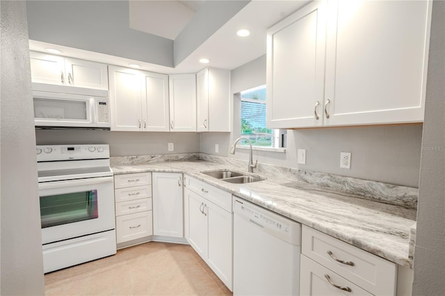 kitchen with white cabinetry, sink, light tile patterned floors, light stone countertops, and white appliances