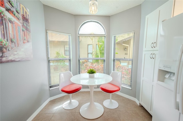 dining space featuring light tile patterned flooring and a textured ceiling