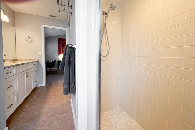 bathroom with vanity, tile patterned flooring, a textured ceiling, and a tile shower