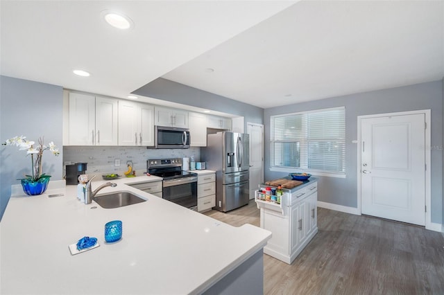 kitchen featuring sink, appliances with stainless steel finishes, backsplash, white cabinets, and kitchen peninsula