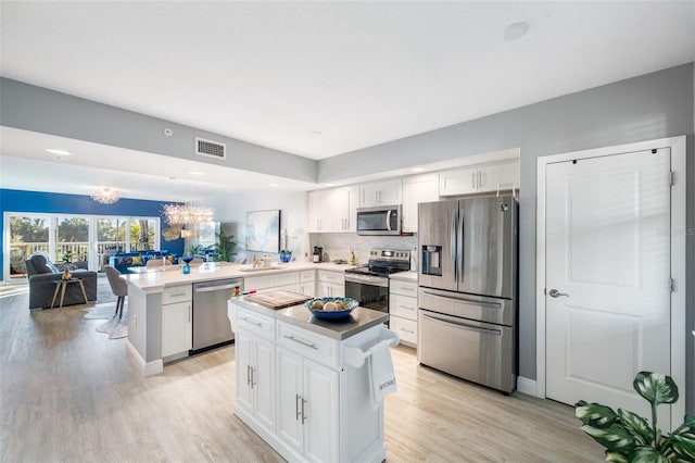 kitchen with white cabinetry, appliances with stainless steel finishes, sink, and kitchen peninsula