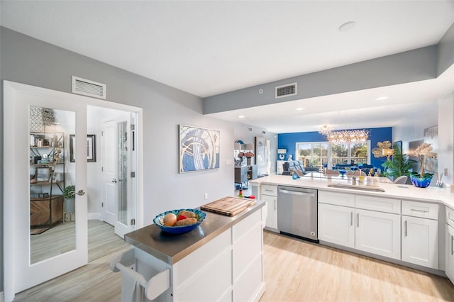 kitchen with light wood-type flooring, stainless steel dishwasher, sink, and white cabinets