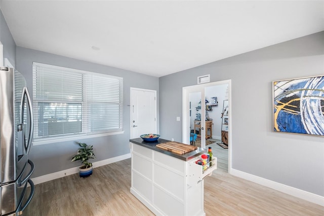 kitchen featuring white cabinetry, stainless steel fridge, light hardwood / wood-style floors, and wooden counters