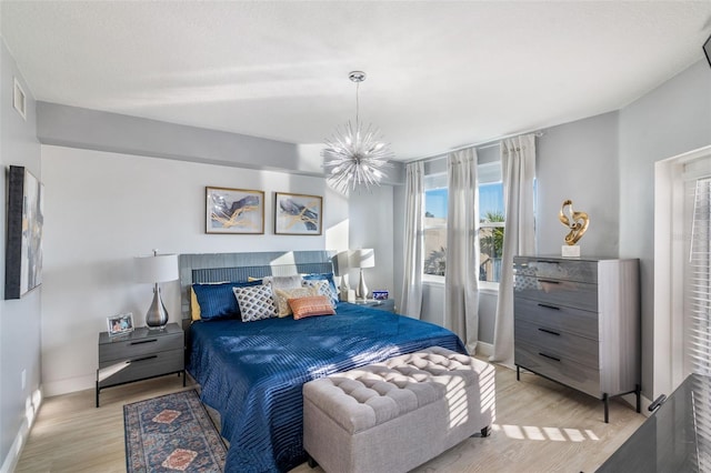 bedroom with an inviting chandelier and light hardwood / wood-style flooring