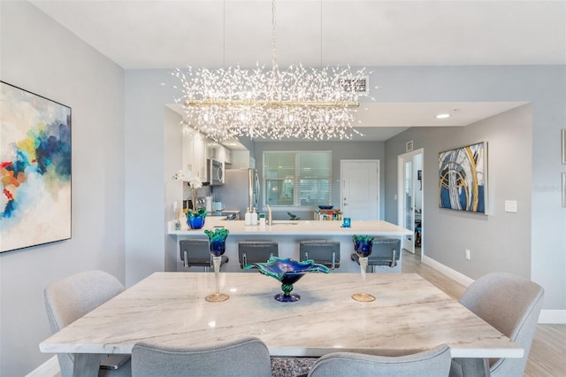 dining space with sink, a notable chandelier, and light wood-type flooring