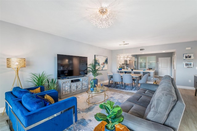 living room with an inviting chandelier and light wood-type flooring