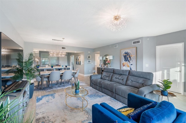 living room with light hardwood / wood-style floors, a textured ceiling, and a notable chandelier