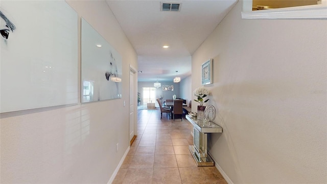 hallway with a chandelier and light tile patterned flooring