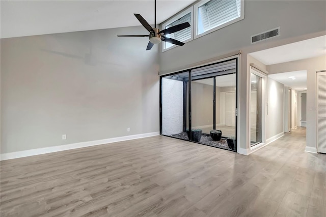 empty room with a towering ceiling, ceiling fan, and light hardwood / wood-style floors