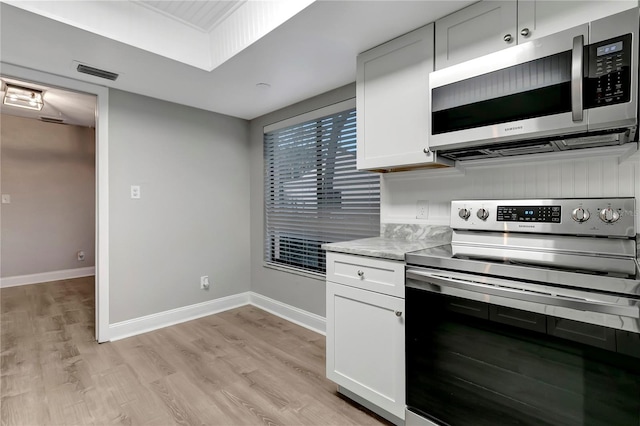 kitchen featuring light stone counters, stainless steel appliances, light hardwood / wood-style floors, and white cabinetry